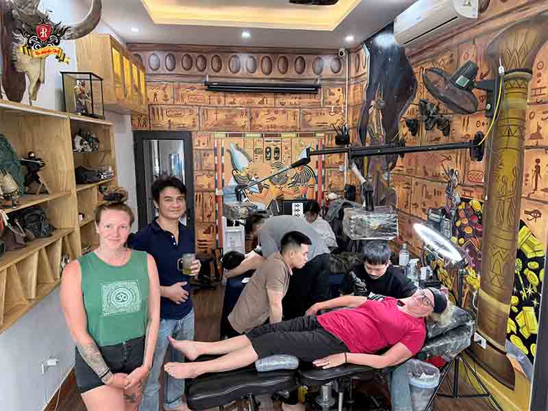 Professional artists in full medical gear crafting an eye of Horus tattoo at Rio Tattoo Studio.