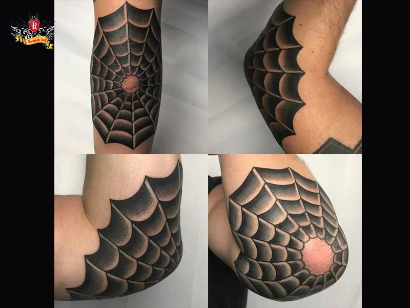 Close-up of a spiderweb on elbow and dots on fingers representing a classic jailhouse tattoo.