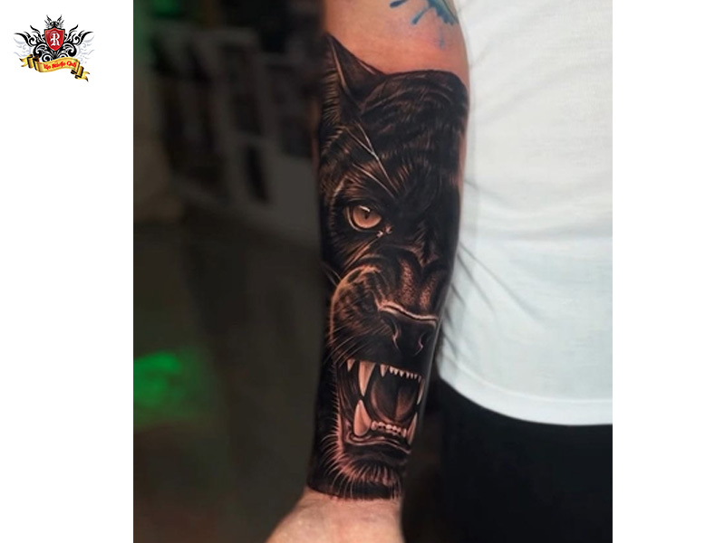 Sharp black panther tattoo on a man's forearm and sleeve under natural light at Rio Tattoo Studio.