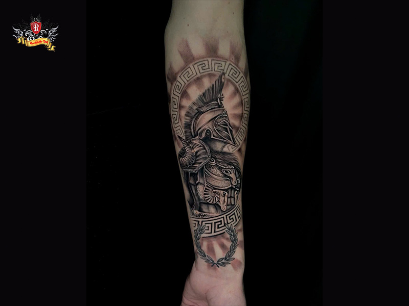Top-down view of a masculine spartan tattoo on a foreign tourist forearm at Rio Tattoo Studio.