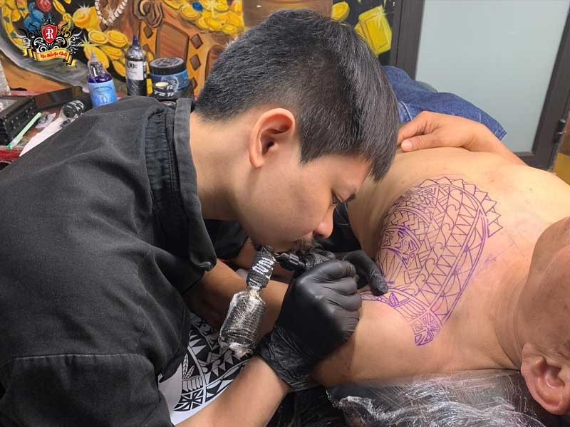 Rio Tattoo Studio artist concentrating on tattooing a foreign client to customize their first tattoo design.