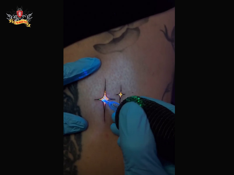 Close-up of a needle inserting luminous ink during a uv tattoo process under ultraviolet light at Rio Tattoo Studio.