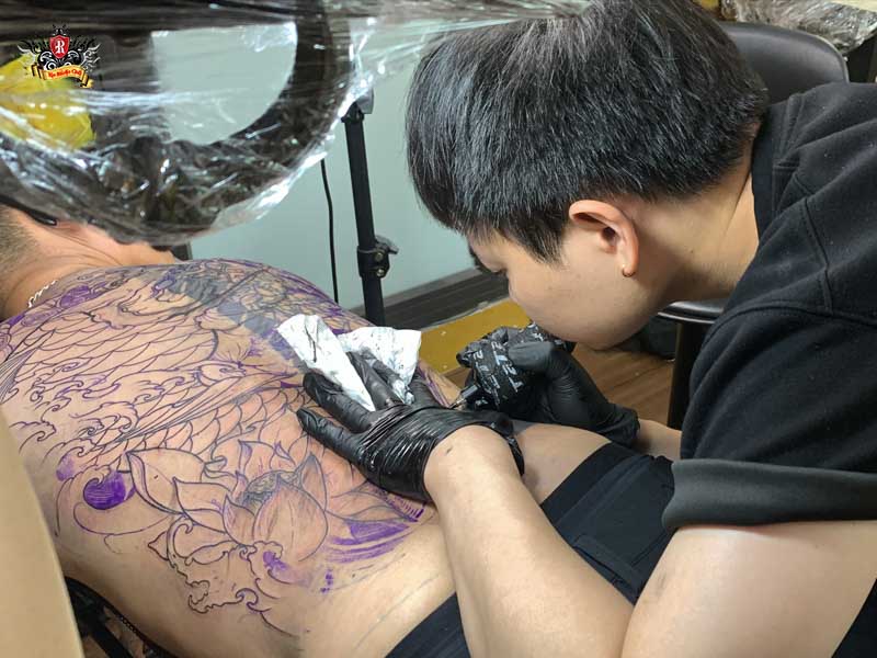 Master artists focusing on a custom uv tattoo design with professional expertise at Rio Tattoo Studio.